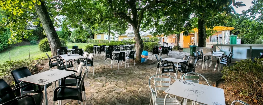 Amplia terraza de "El Rincón de Koller", con mesas dispuestas entre árboles